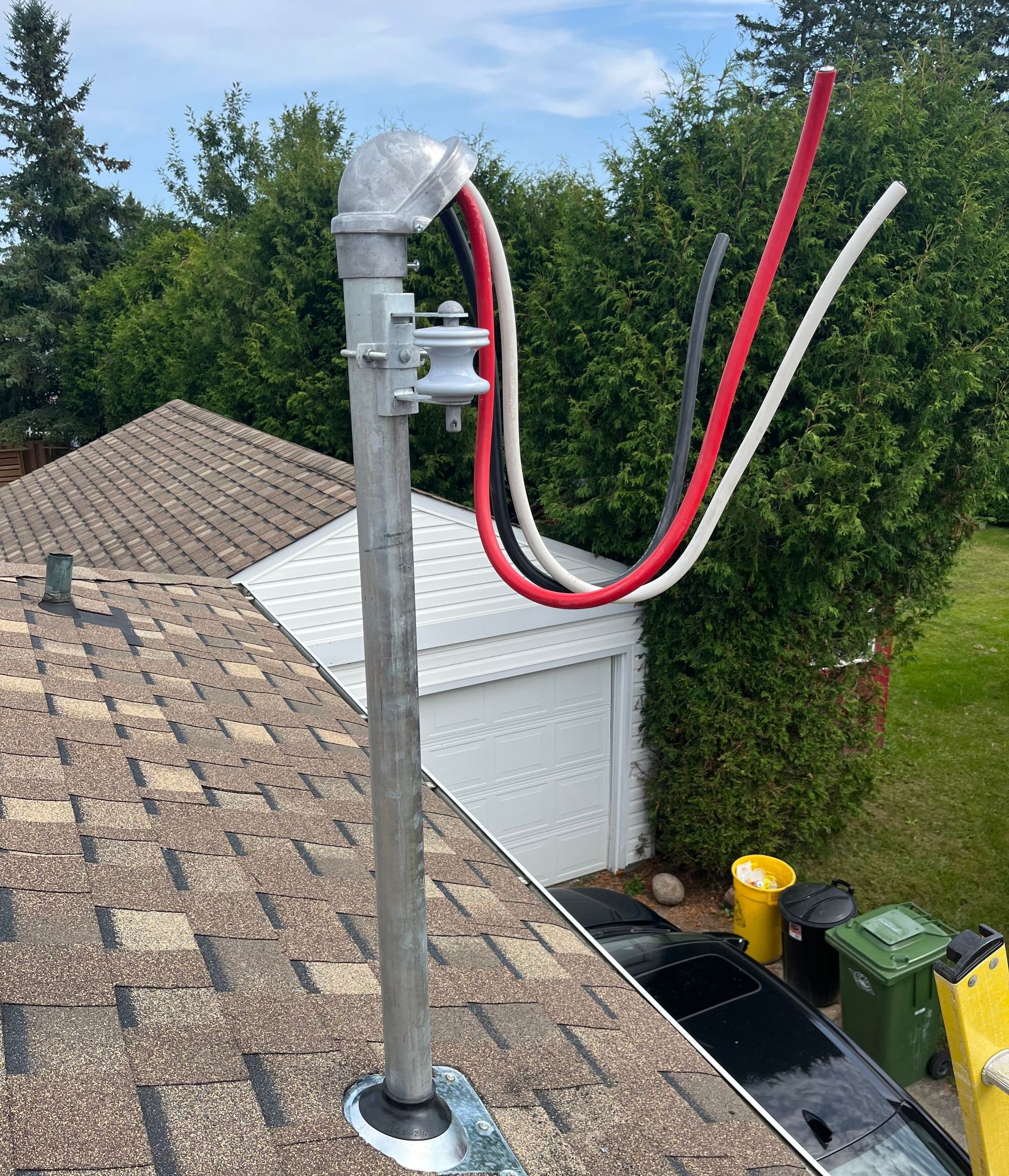 A pole with wires attached to it is sitting on top of a roof.