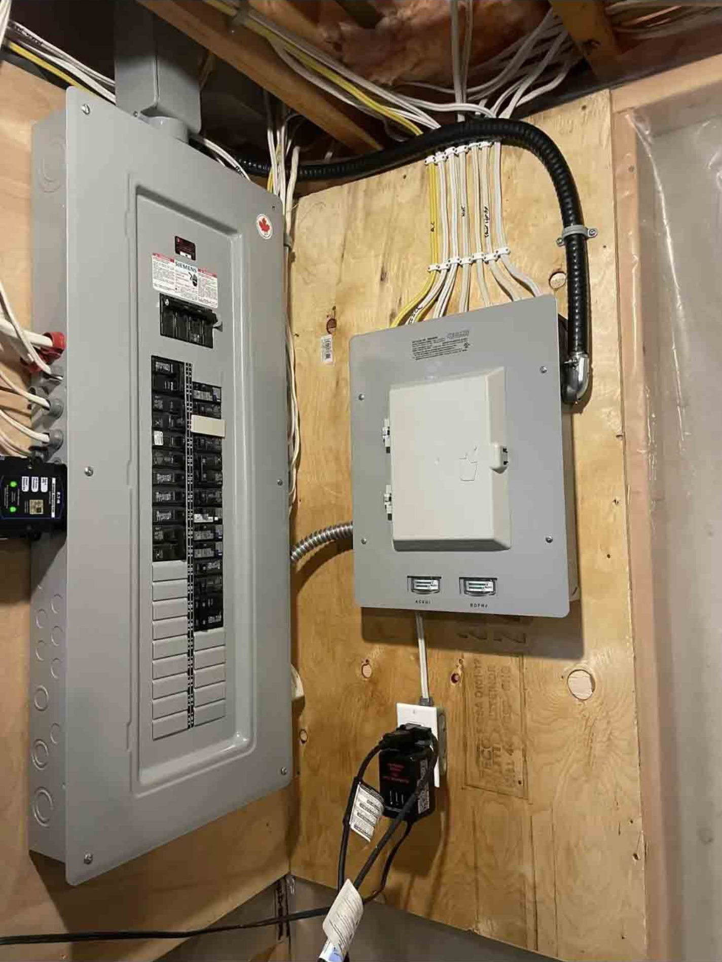 Open electrical panel with circuit breakers and distribution box on a wooden board.