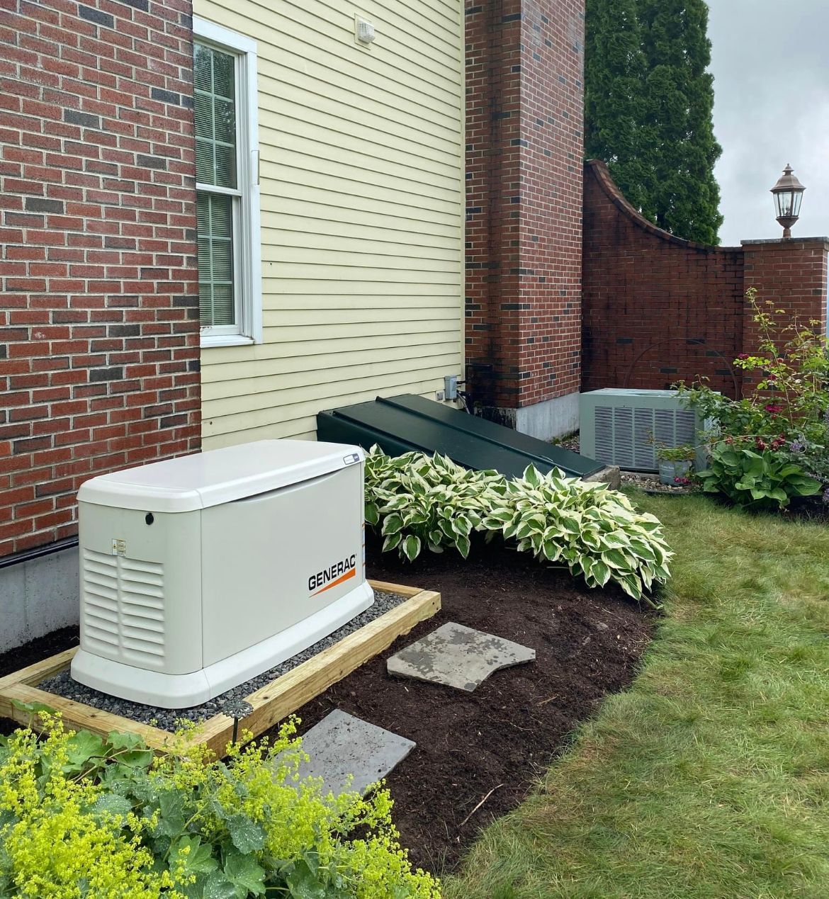 A generator is sitting in the backyard of a brick house.