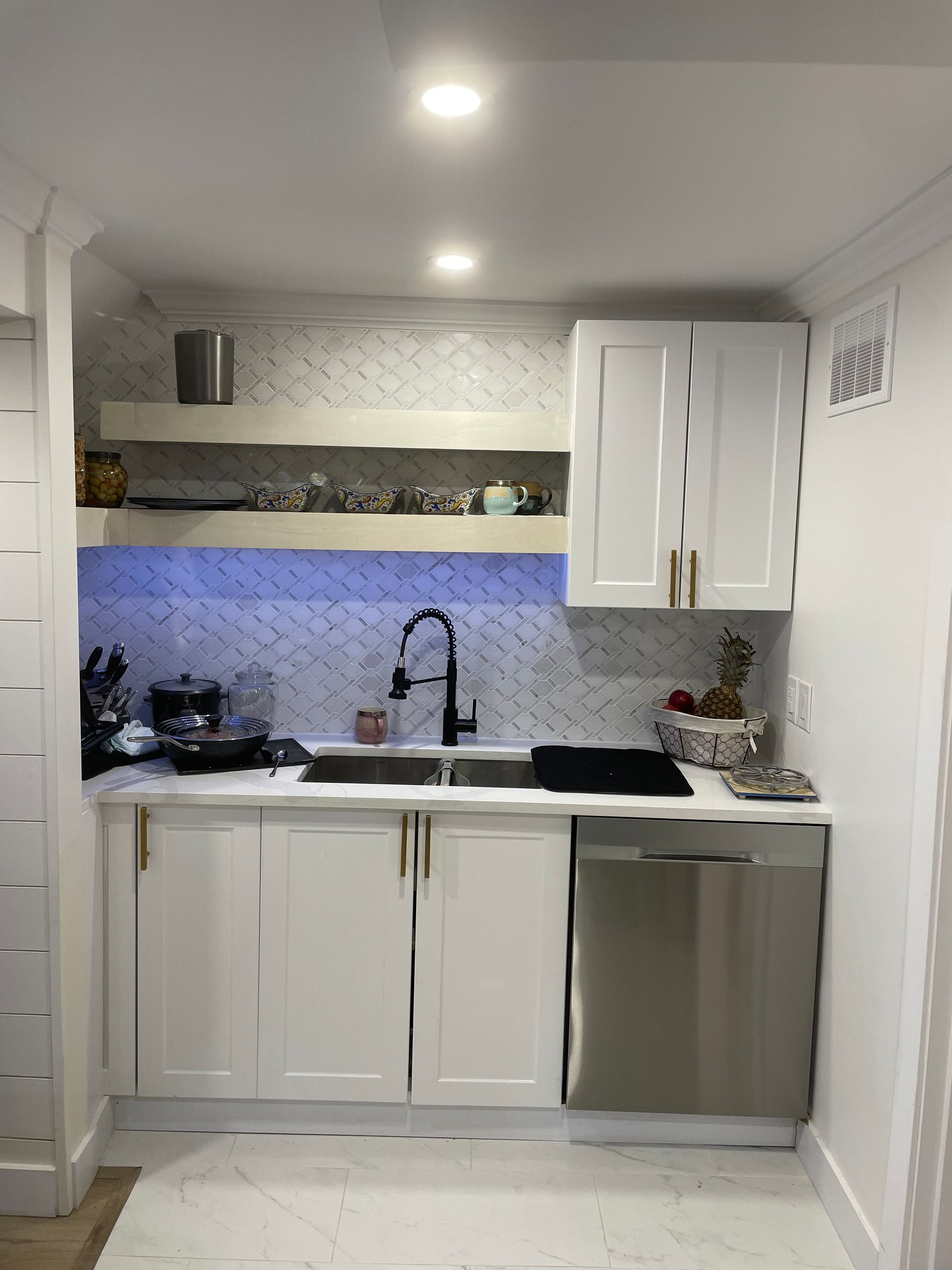 A kitchen with white cabinets , a sink , and a stainless steel dishwasher.
