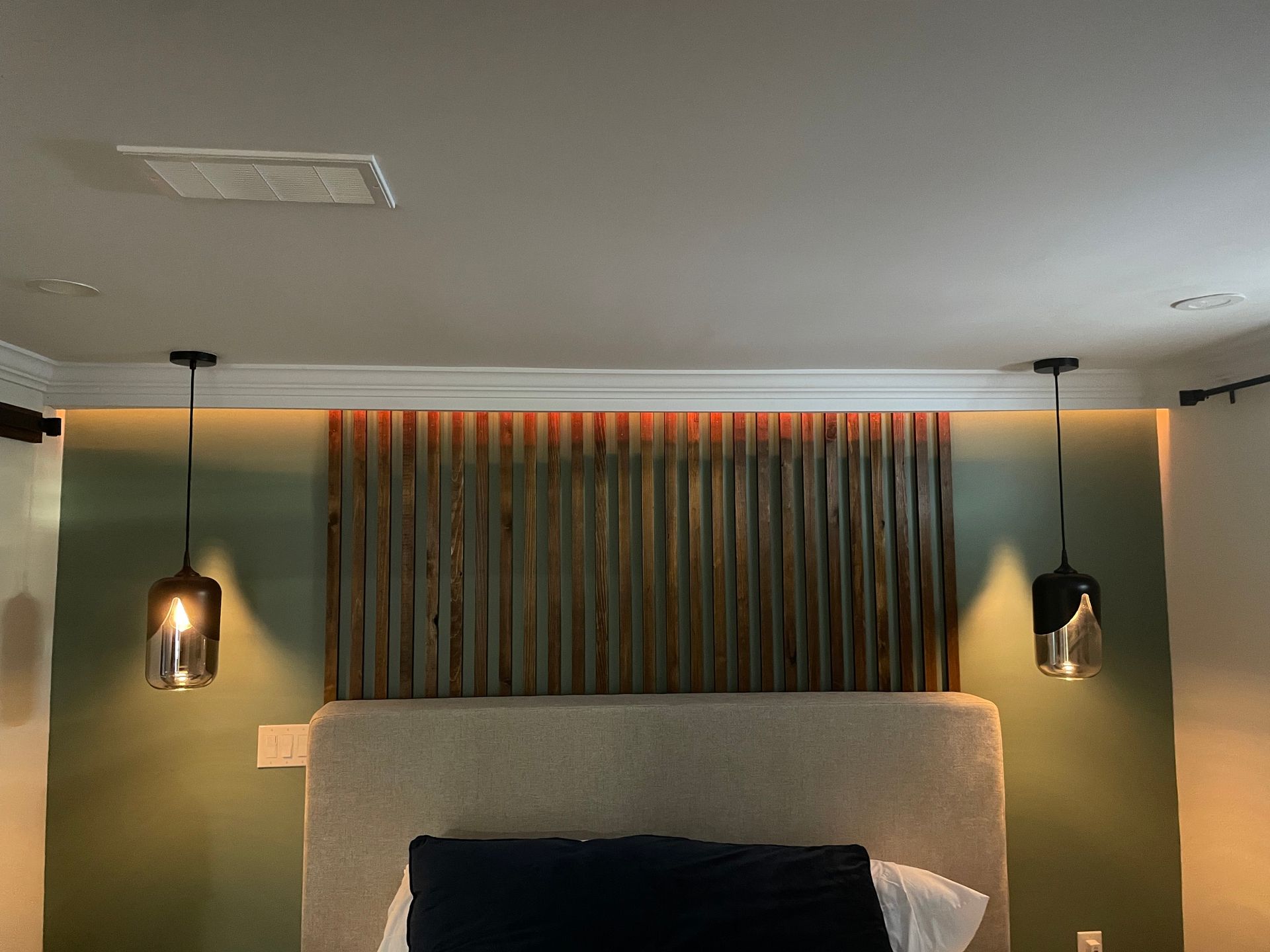 A bedroom with a bed , lamps and a wooden headboard.