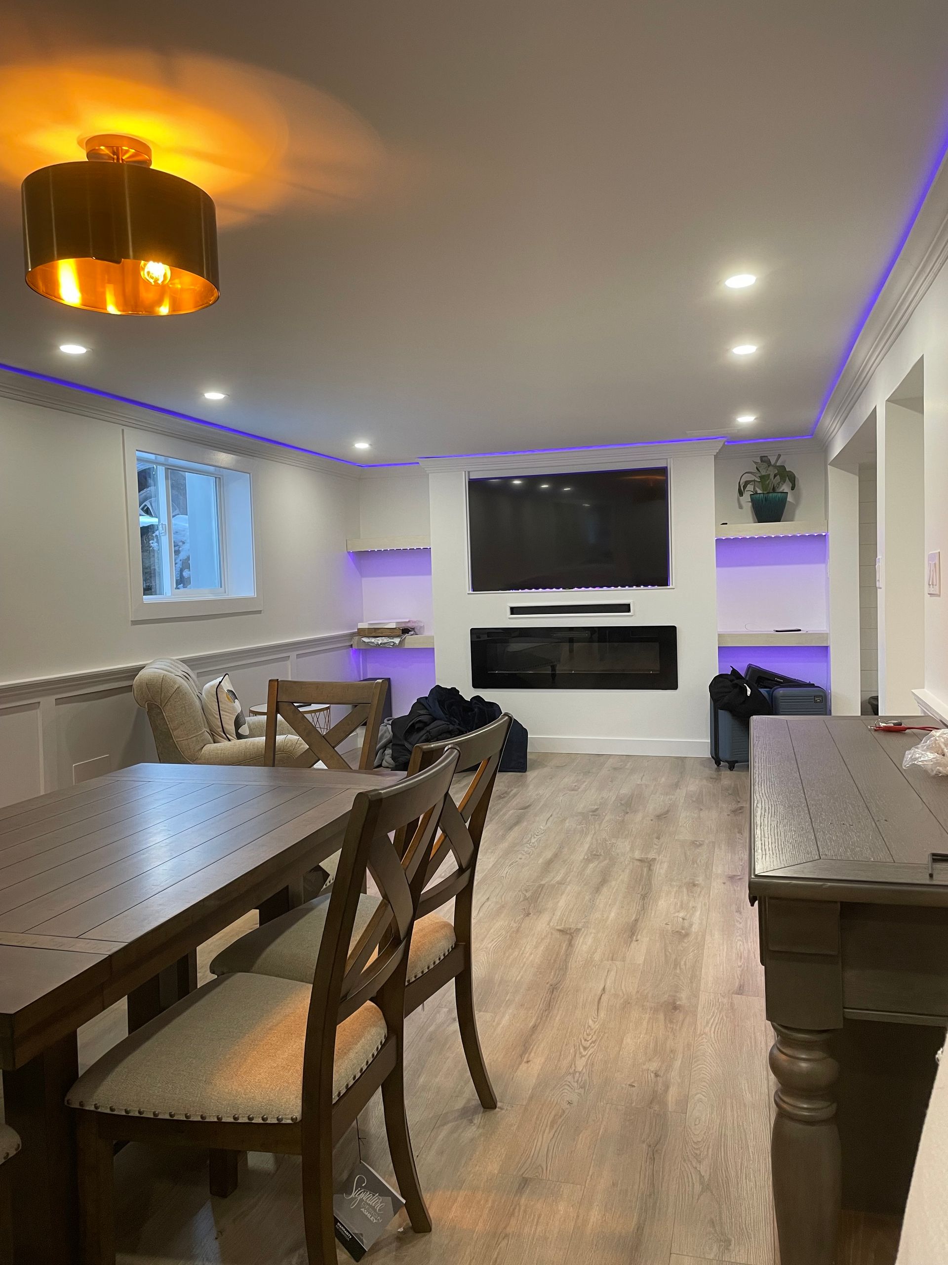 A living room with a table and chairs and a flat screen tv.