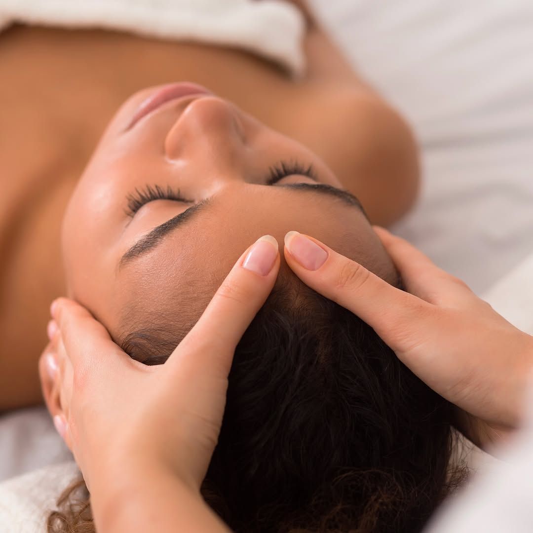Une femme reçoit un massage de la tête les yeux fermés