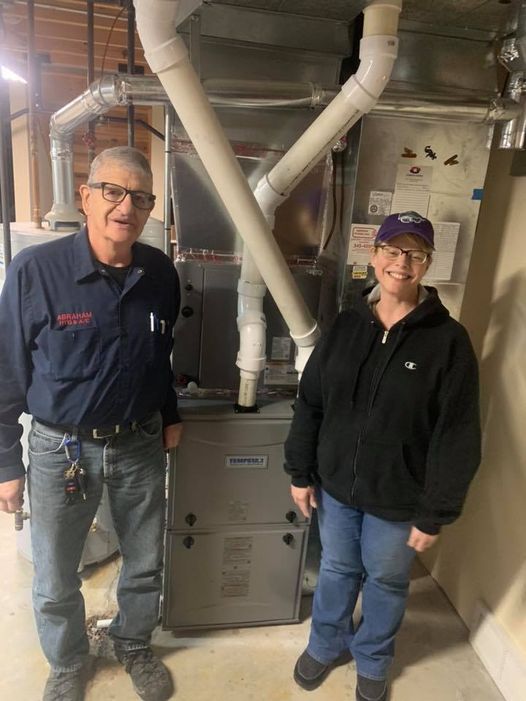 a man and a woman are standing next to a furnace in a basement .