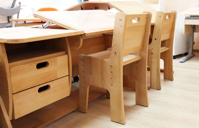 Un tavolo e sedie in legno a misura di bambino in una stanza luminosa, con cassetti sotto la scrivania.