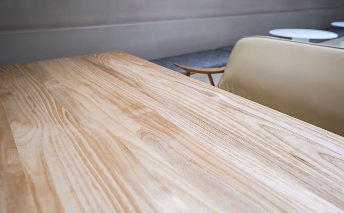 Tavolo in legno in un angolo del caffè con sedute beige e un piccolo tavolino rotondo nelle vicinanze.
