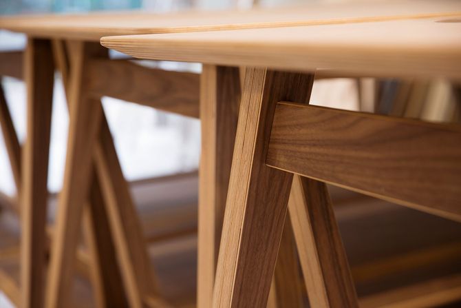 Primo piano di sedie e tavolo in legno in una stanza calda e illuminata da una luce soffusa.