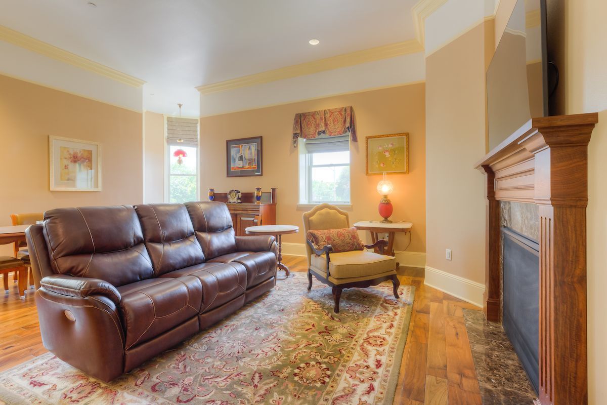 Living room with brown leather reclining sofa, armchair, fireplace, and wood flooring.