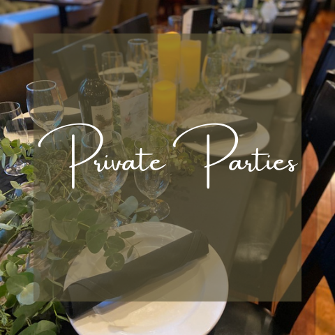 Table set for private party with candles, wine glasses, and greenery.