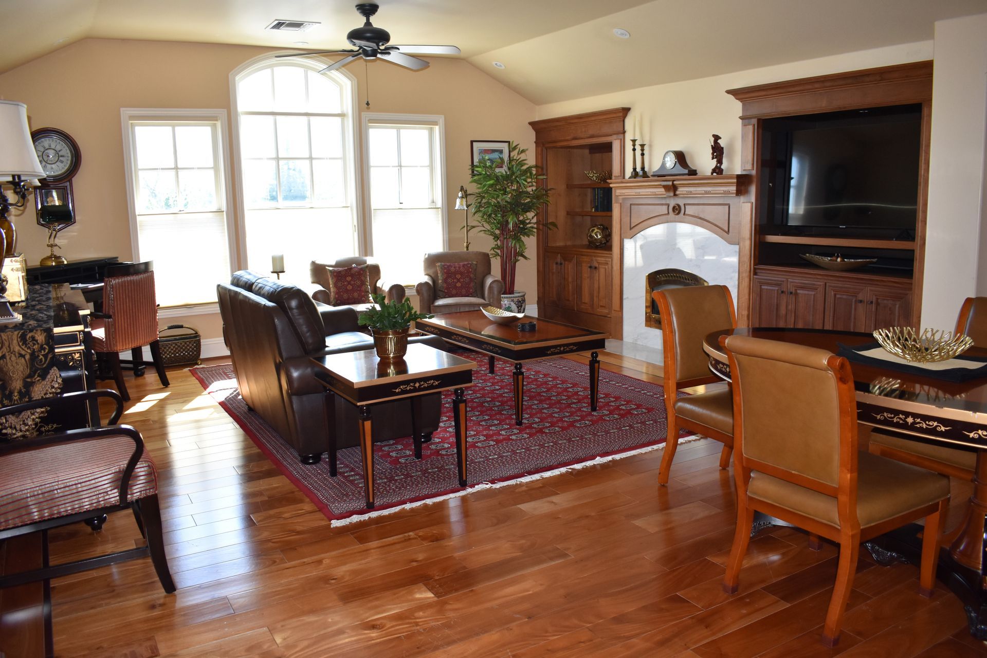 Living room with hardwood floors, leather furniture, a fireplace, and large windows.