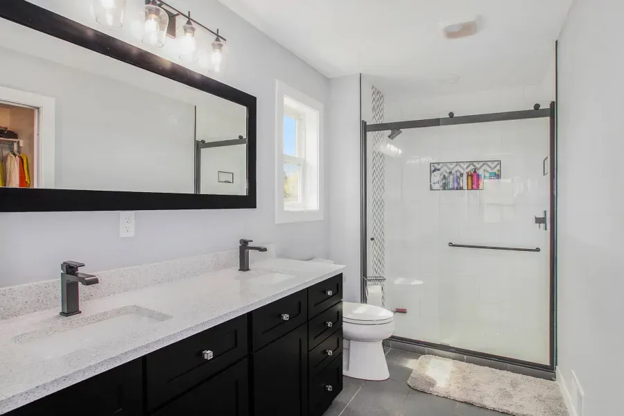 A bathroom with two sinks , a toilet , and a shower.