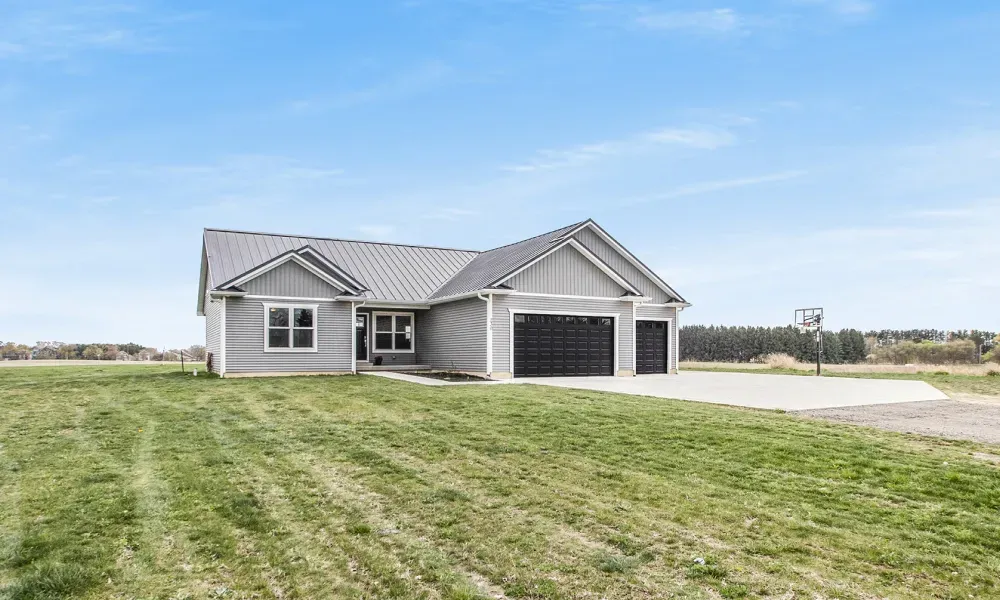 A house is sitting in the middle of a lush green field.