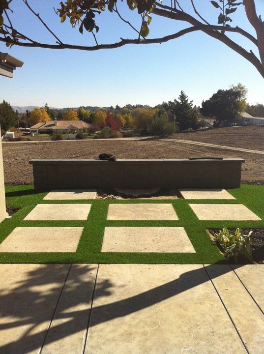 Patio with green turf grid, concrete bench, and open park view under bare tree branches