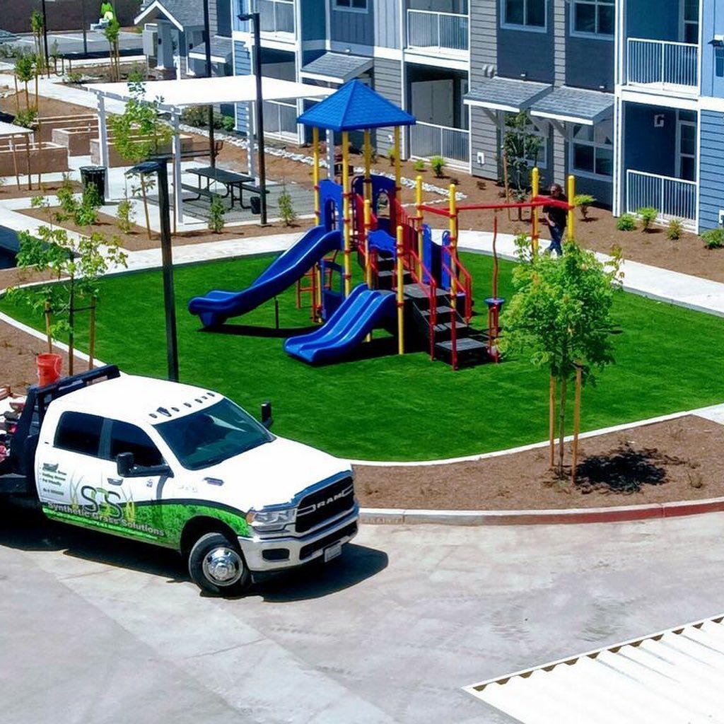 White utility truck near a colorful playground in an apartment courtyard