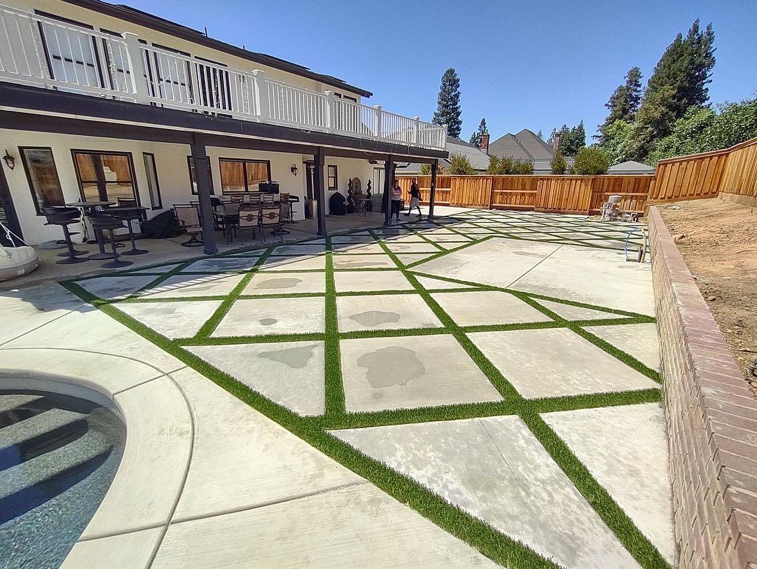 Backyard patio with concrete pavers, grass strips, house porch, and a pool edge on the left.