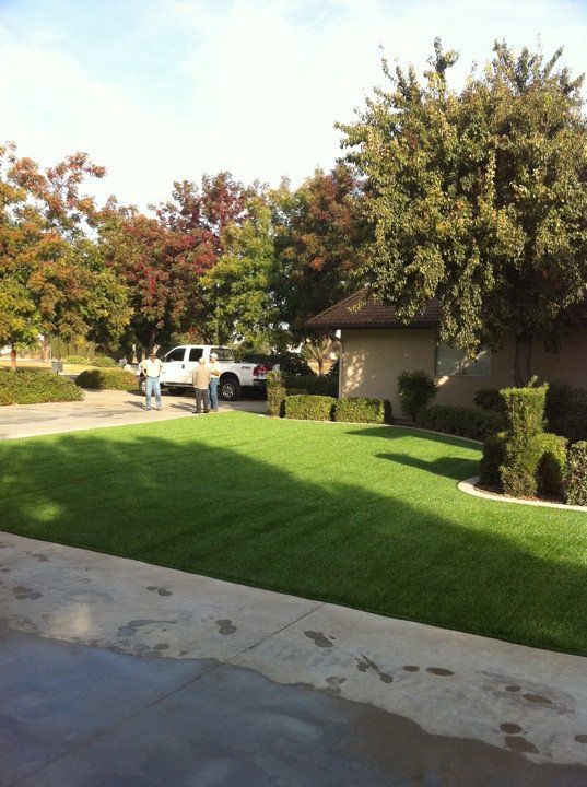 Suburban driveway and lawn with a white pickup truck beside a house and trees in autumn.