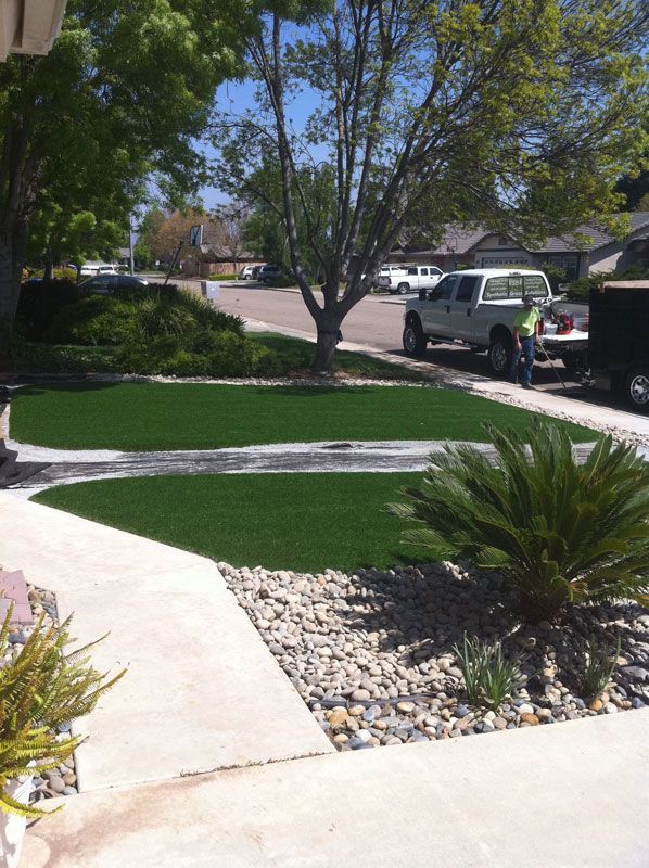 Curved front yard walkway, green lawn, and gravel landscaping with parked vehicles in a suburban neighborhood