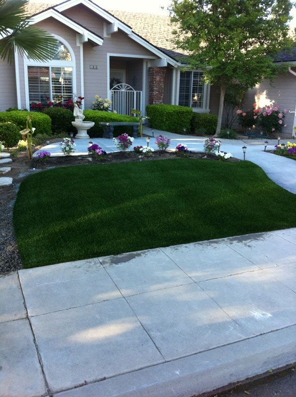 Suburban house front yard with manicured lawn, flower beds, and a concrete walkway