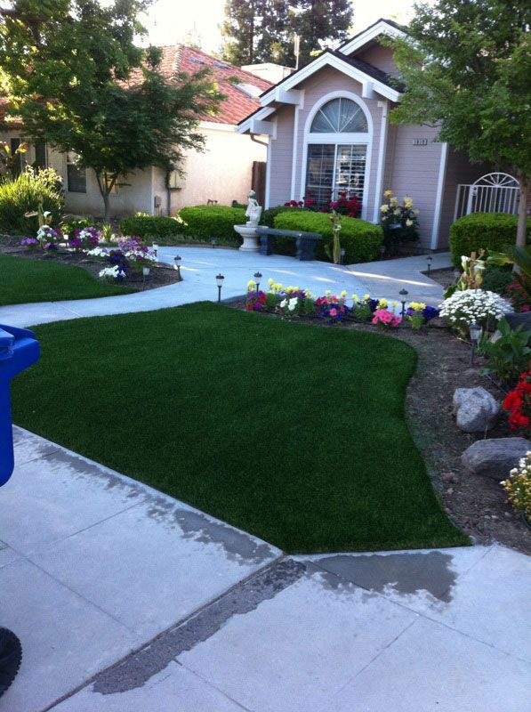 Front yard garden with curved lawn, colorful flowers, and a house entrance with arched window