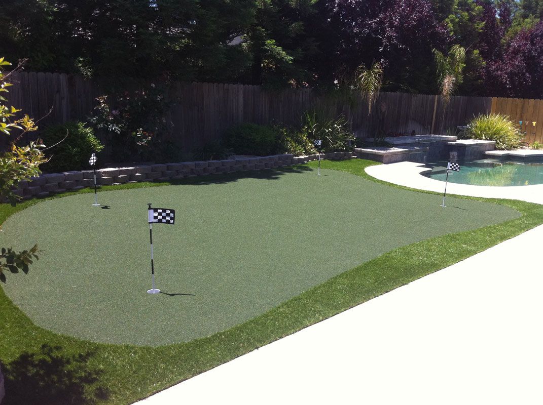 Backyard putting green with a golf flag and a curved pool edge nearby