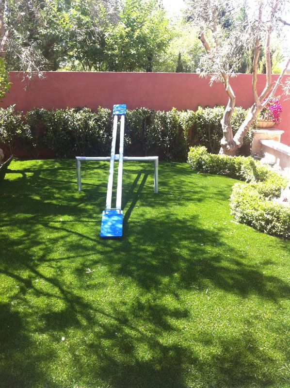 Garden lawn with a blue and white play structure under a shaded canopy.