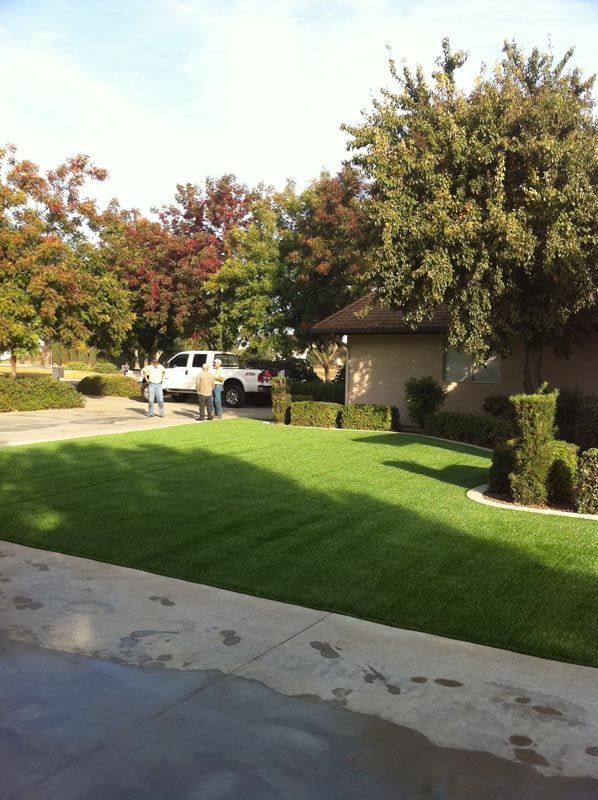 Suburban driveway with a white pickup truck, green lawn, trees, and a house in the background