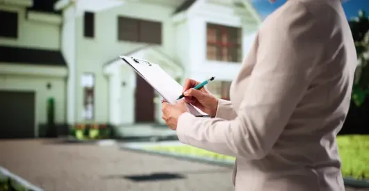 Person taking notes on a clipboard outside a house for a home inspection