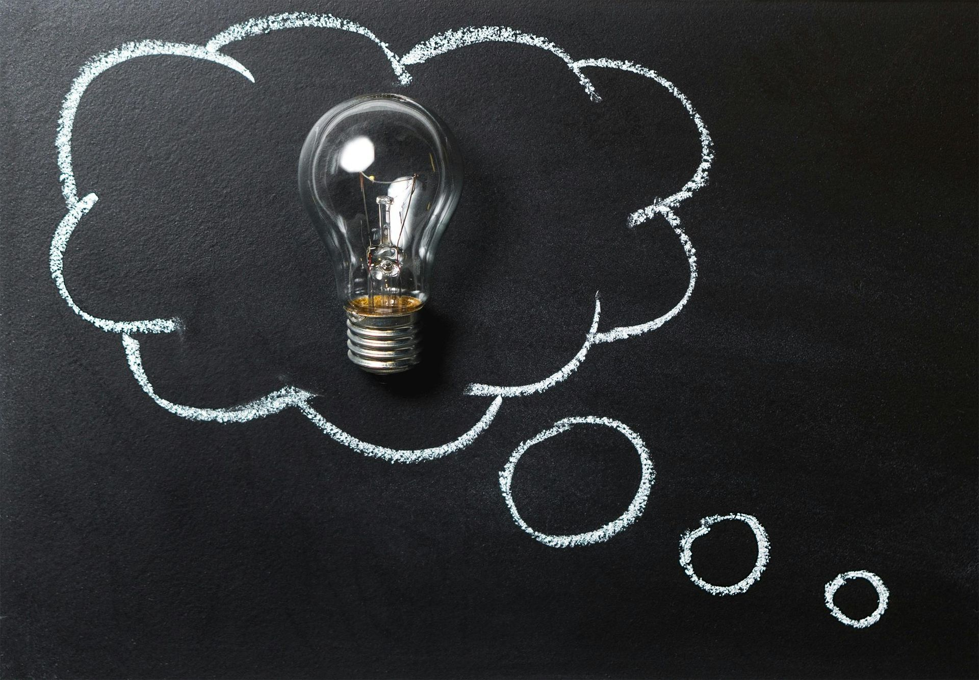 Digital Marketing, Website design Cambridge, Wisconsin. Light bulb inside a chalk-drawn thought bubble on a black chalkboard, symbolizing an idea.