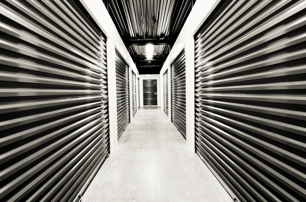 Storage Units in A Long Corridor, Metal Doors with A Central Light Fixture — Complete Sheds In Campbelltown, NSW