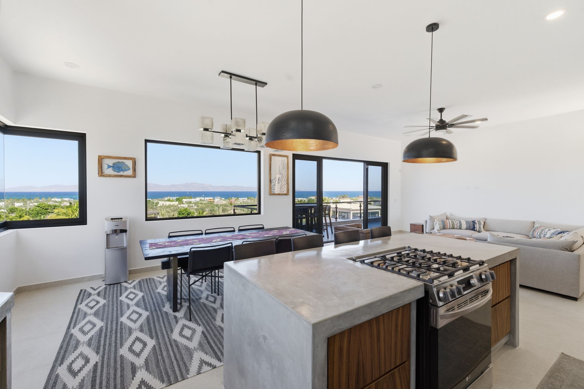 Open-concept kitchen and dining area with ocean views. Modern decor with large windows, island, and dining table.