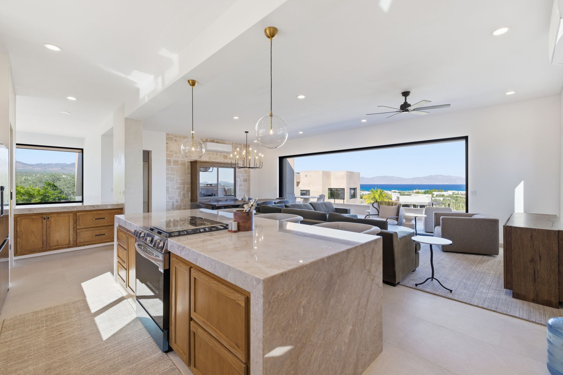 Kitchen with island, light wood cabinets, and large window overlooking ocean view.