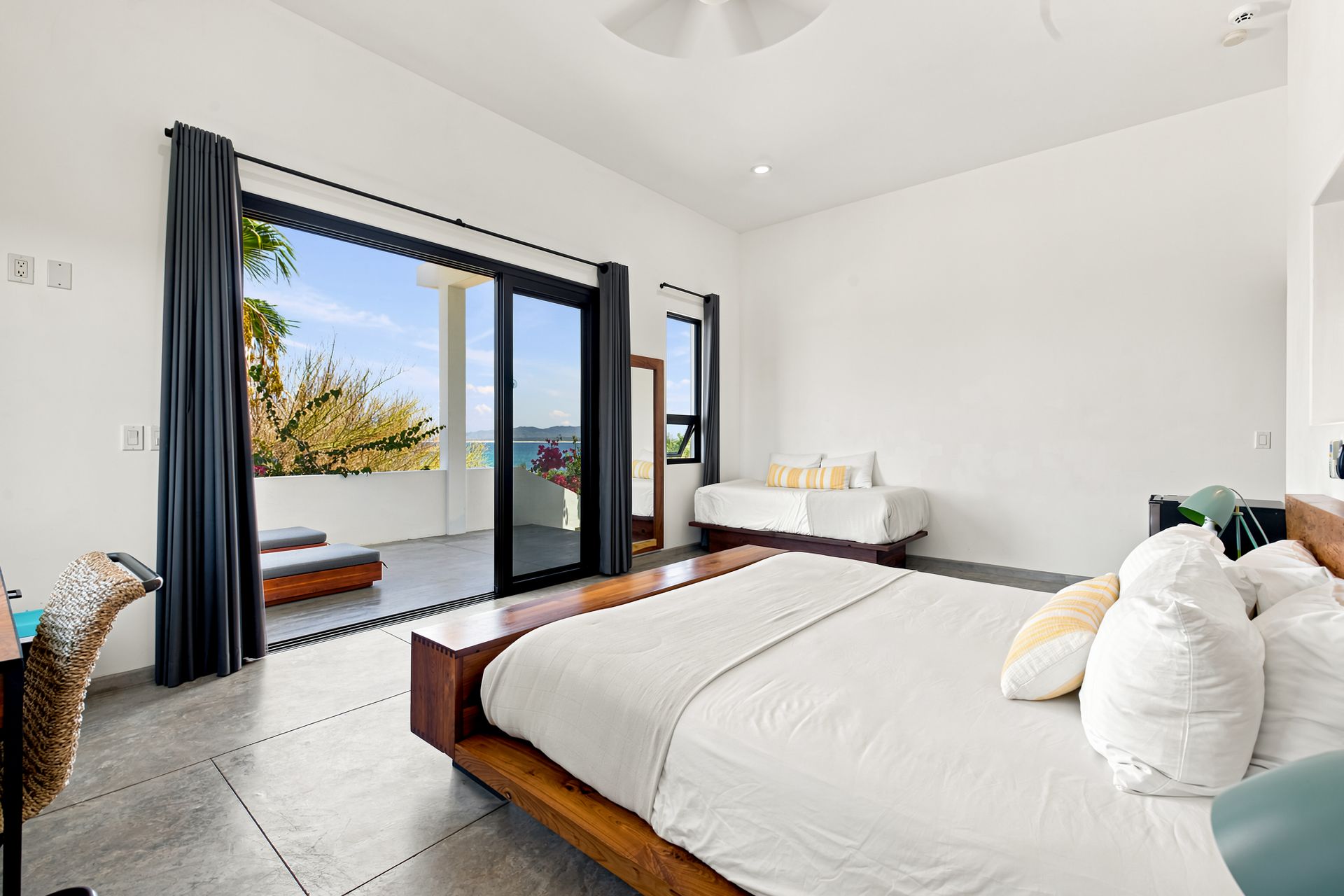 Bedroom with a bed, extra bed, open glass doors, and a view of the ocean.