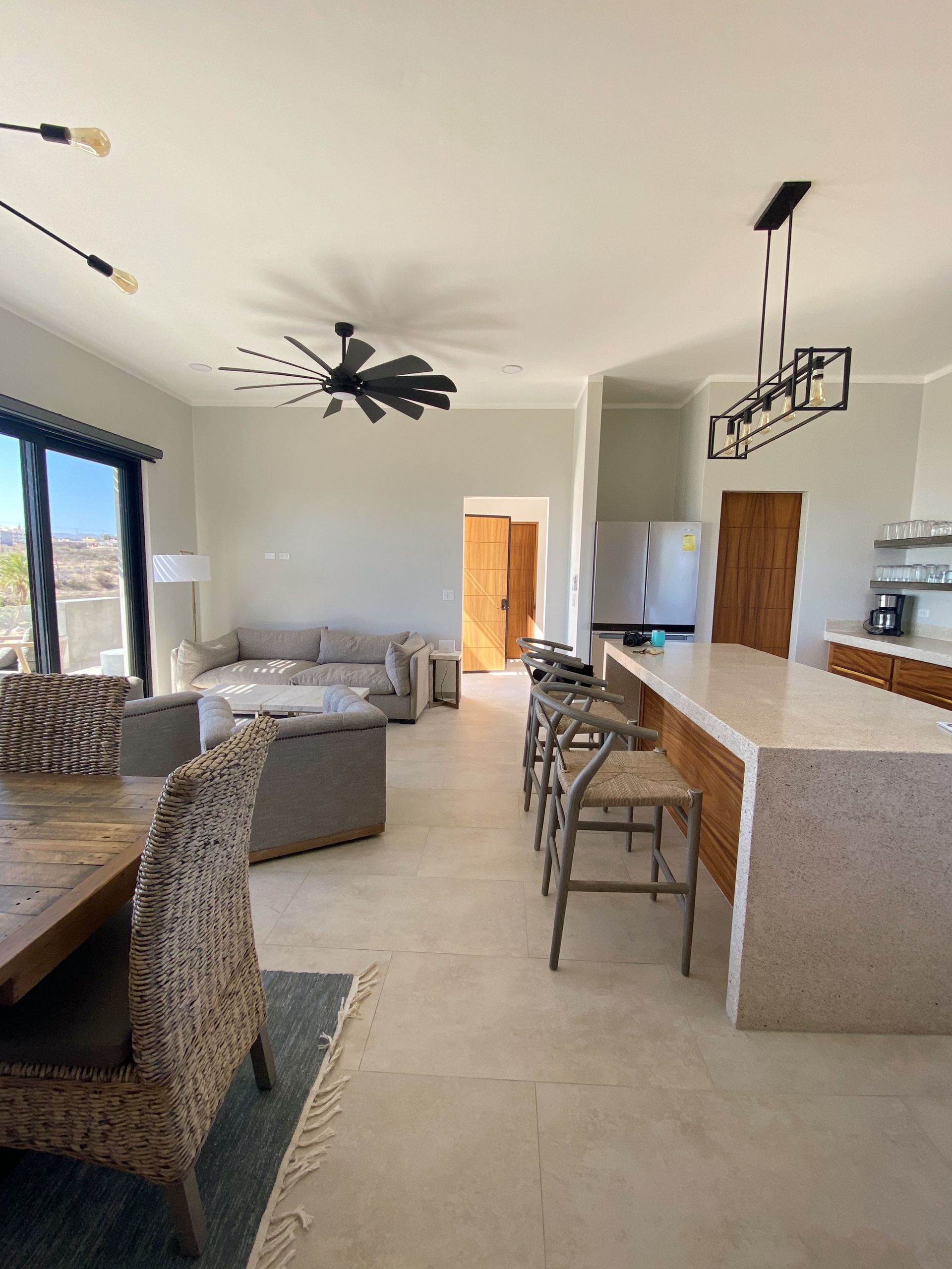 Open-concept living space with kitchen island and dining area. Neutral colors, natural light, and modern fixtures.