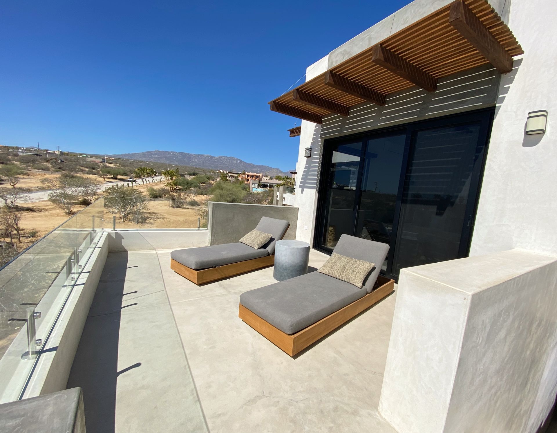 Two lounge chairs on a concrete deck overlook a landscape with mountains in the distance.