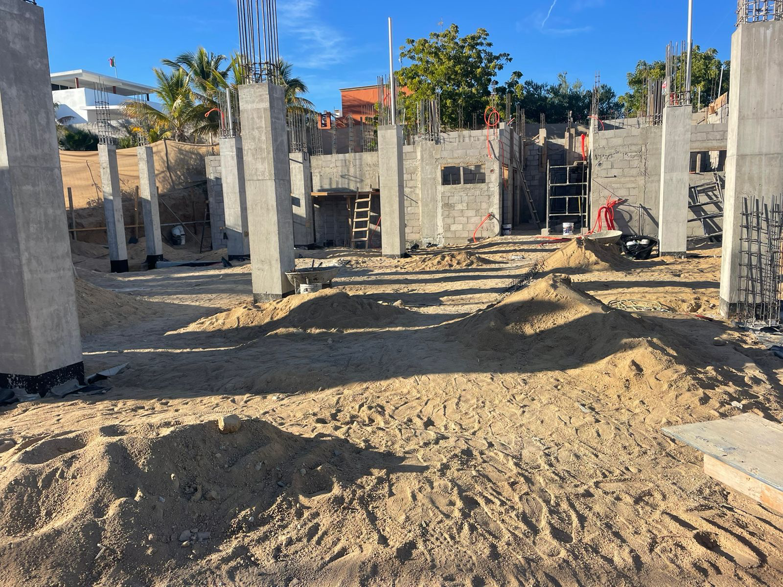Construction site with concrete columns and dirt ground under a blue sky
