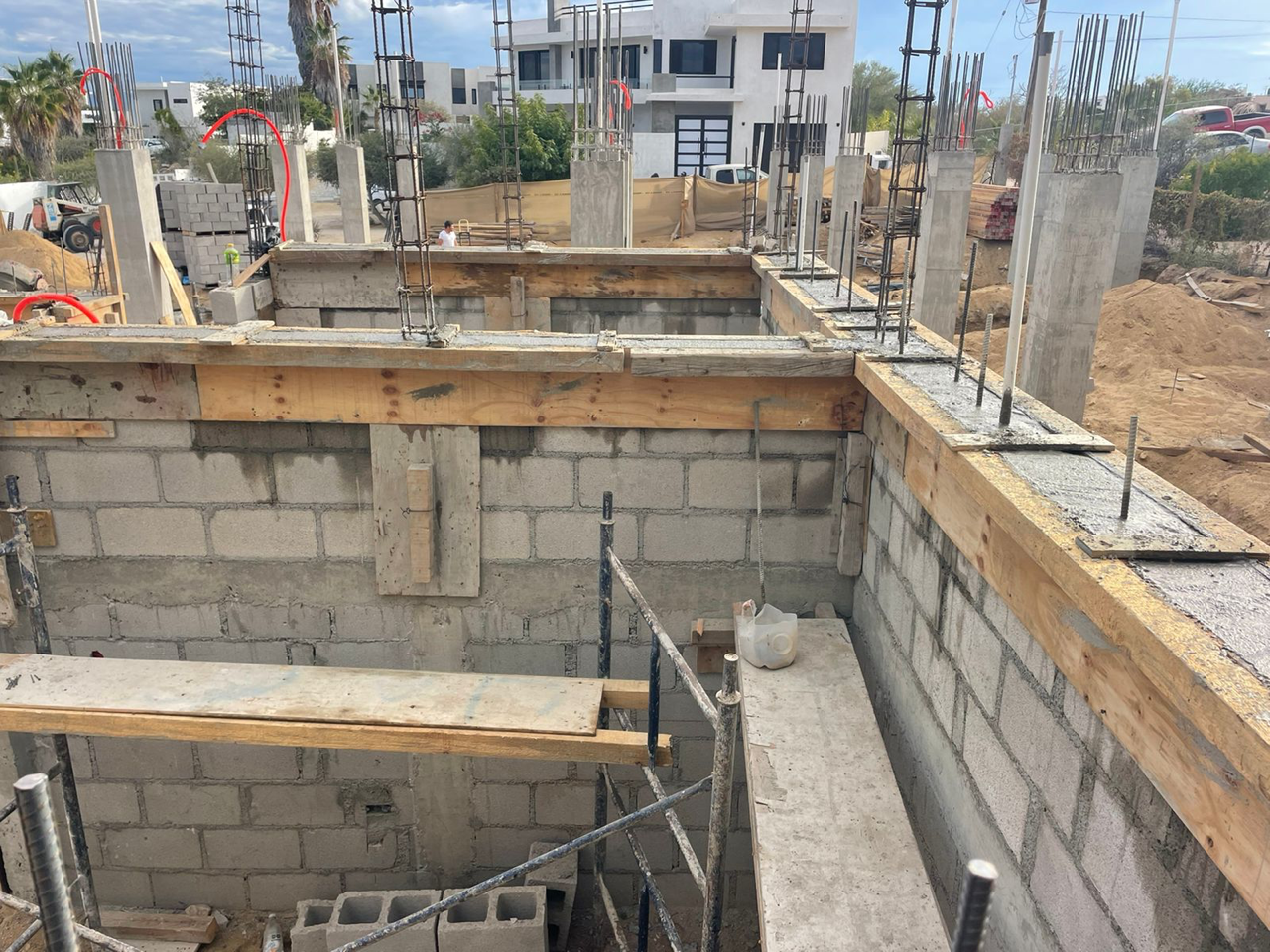 Construction site with cinder block walls and wooden formwork around an unfinished foundation trench