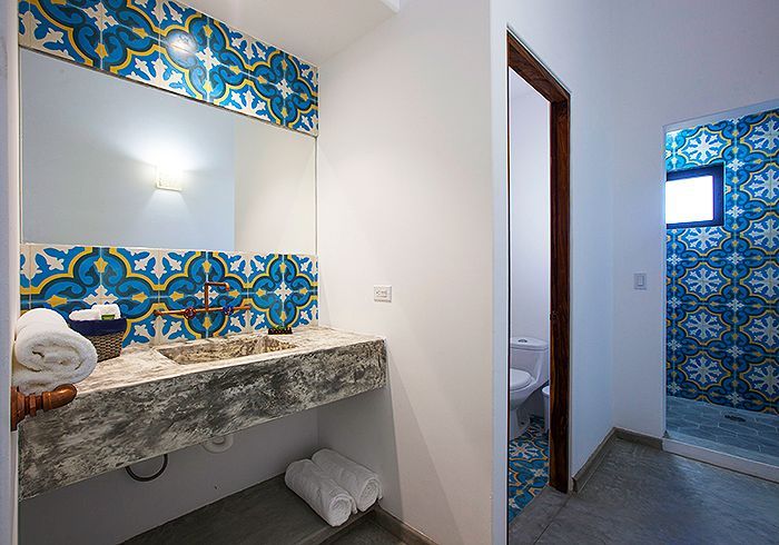 Bathroom with patterned blue tiles, granite sink, and white towels. Doorway to shower visible.