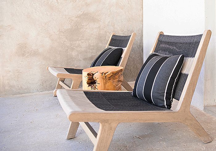Two wooden lounge chairs with black and white cushions, small wooden table.