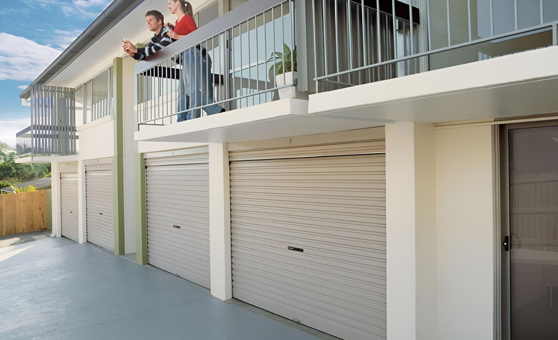 A Couple Standing On A Balcony Overlooking A Row Of Garage Doors — Gold Coast Door Centre In Burleigh Heads, QLD
