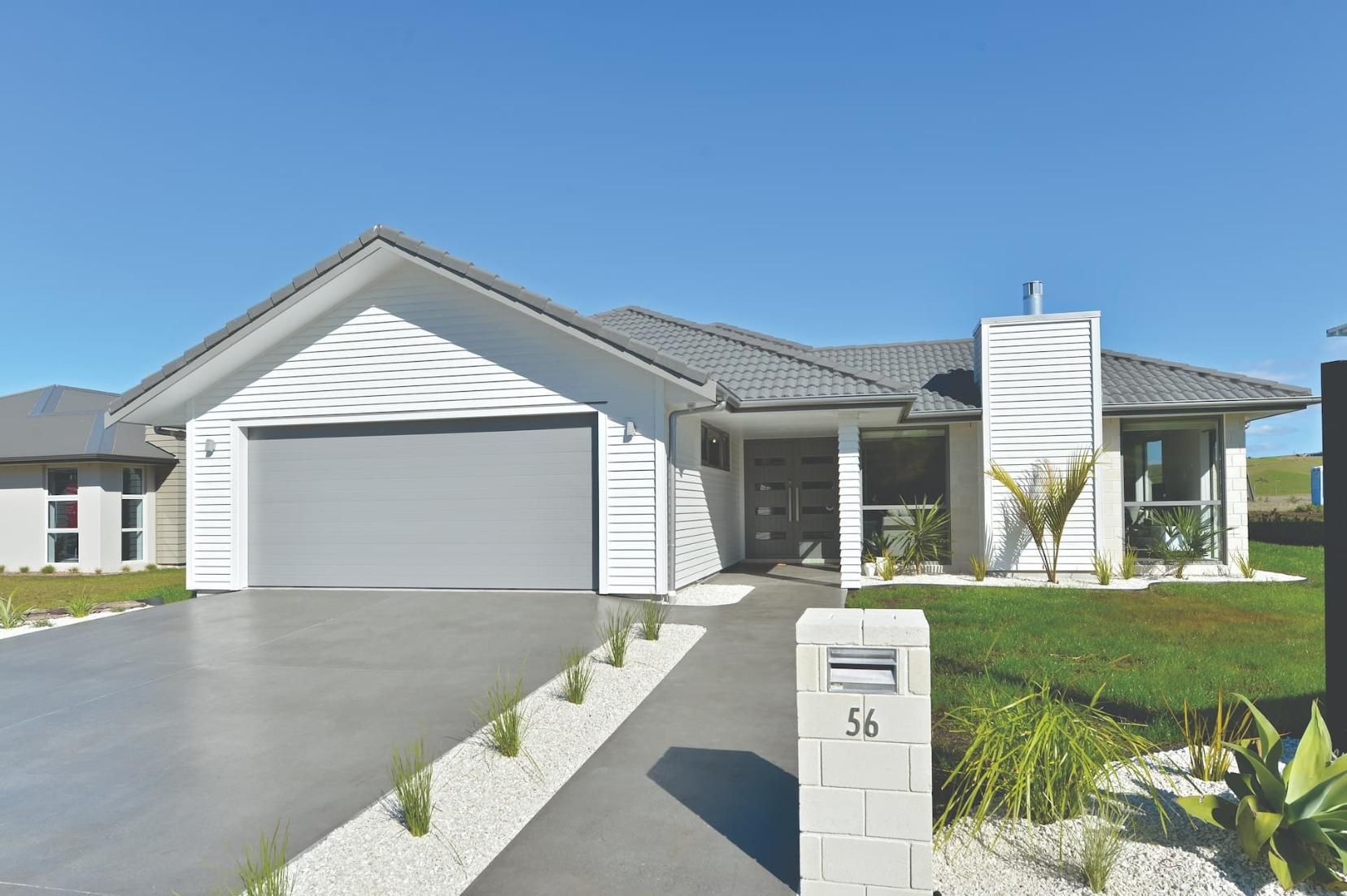 A Large White House With A Gray Garage Door And A Mailbox In Front Of It — Gold Coast Door Centre In Burleigh Heads, QLD