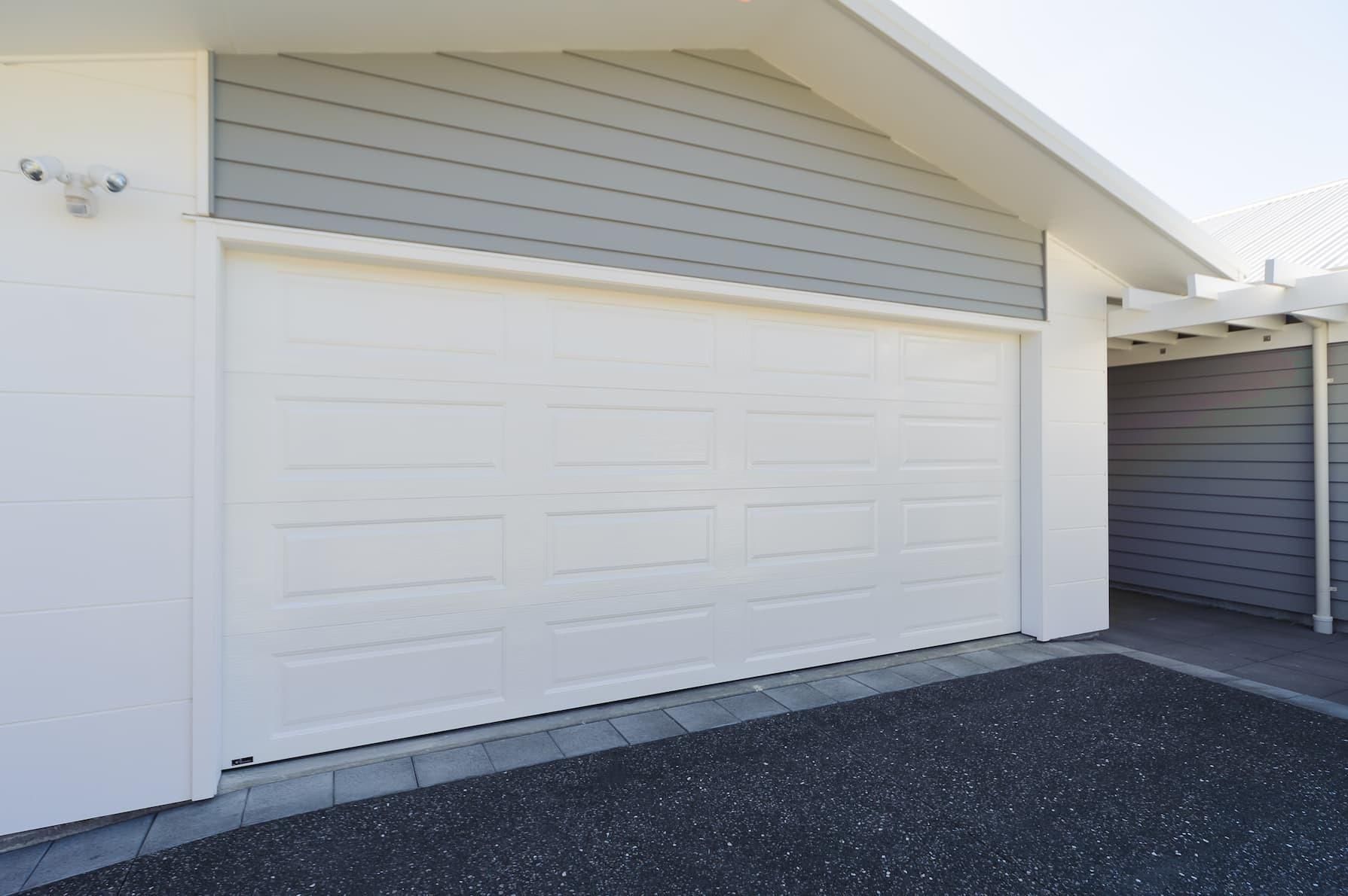 A White Garage Door Is Open In Front Of A House — Gold Coast Door Centre In Burleigh Heads, QLD