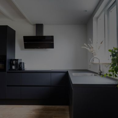 A kitchen with black cabinets , a sink , a coffee maker , and a window.
