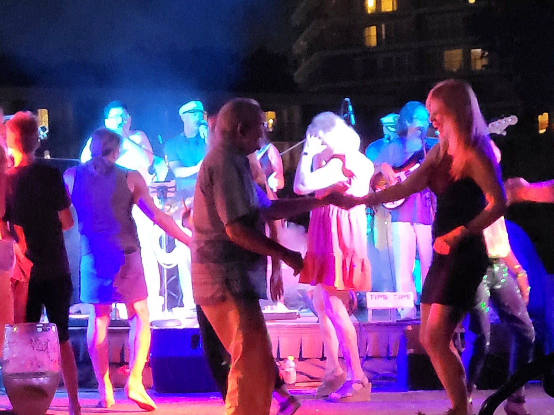 A group of people are dancing on a stage at night