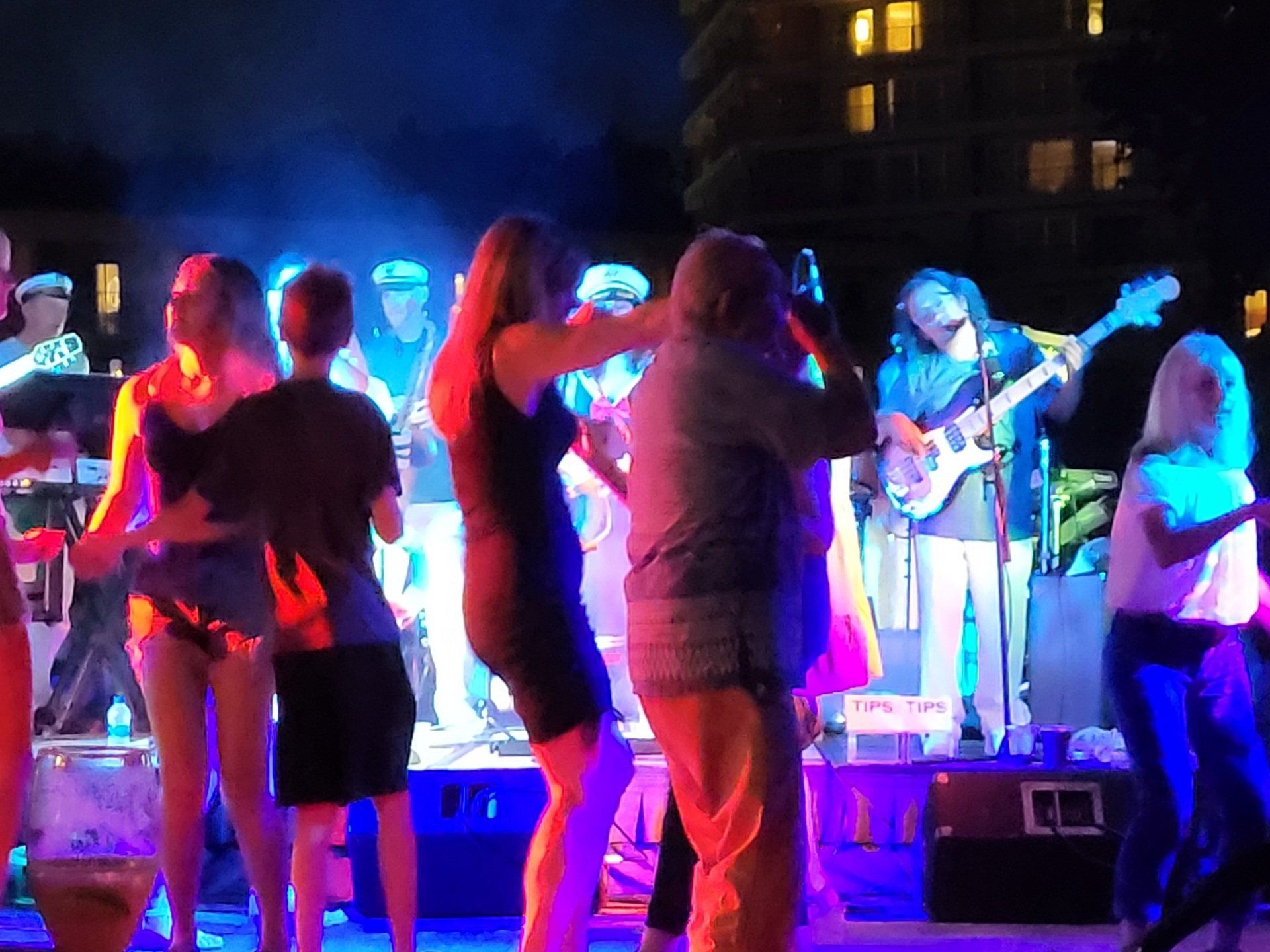 A group of people are dancing in front of a band on a stage.