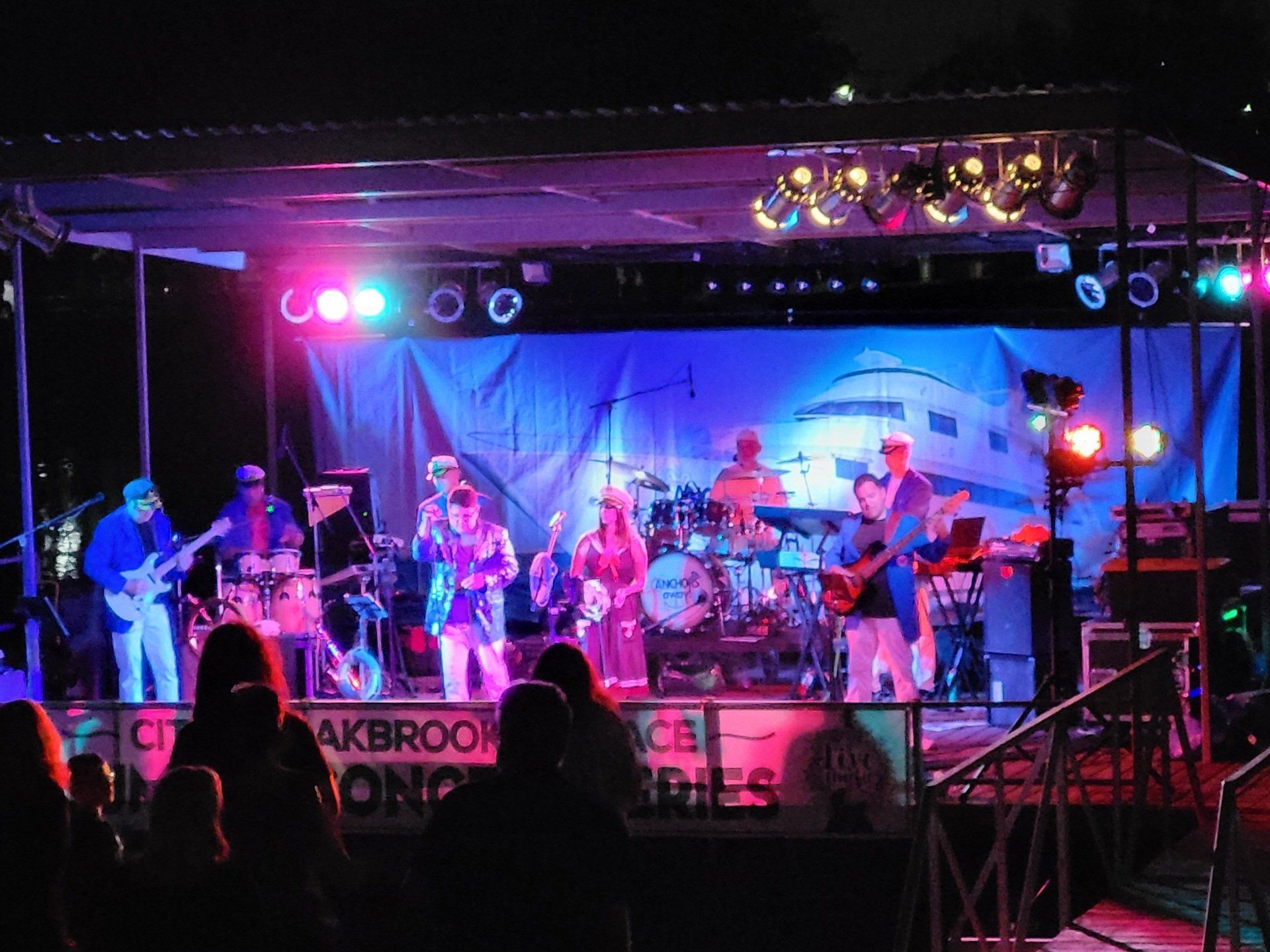 A band is playing on a stage in front of a sign that says akbrook memories