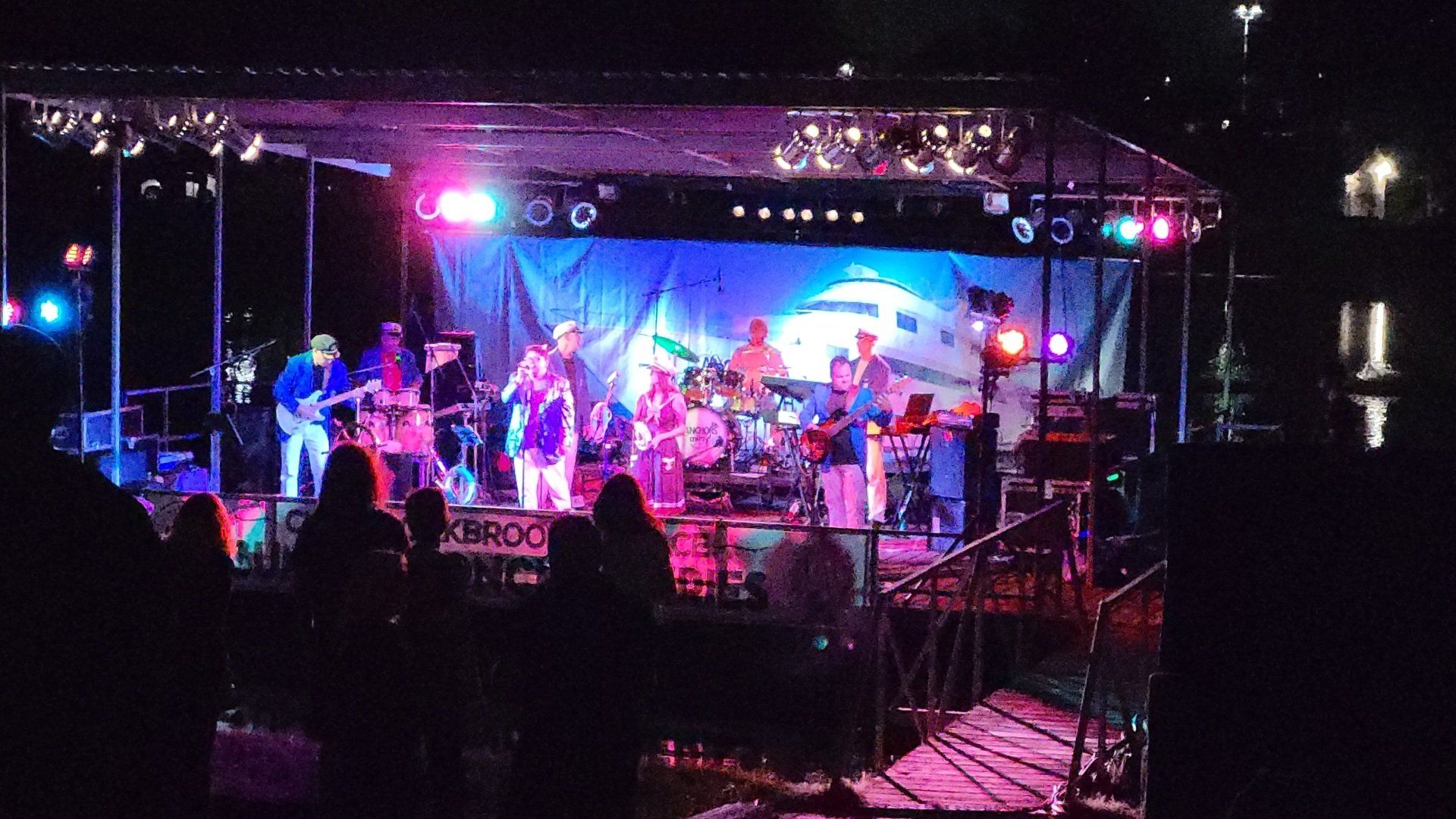 A group of people are playing instruments on a stage at night.
