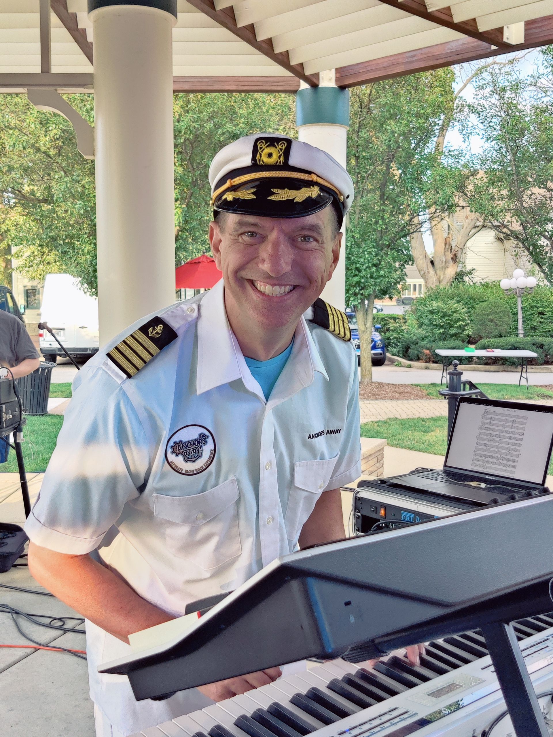 A man in a captain 's hat is playing a keyboard.