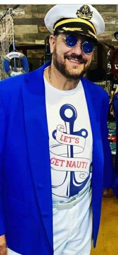 A man is wearing a blue jacket and a captain 's hat.