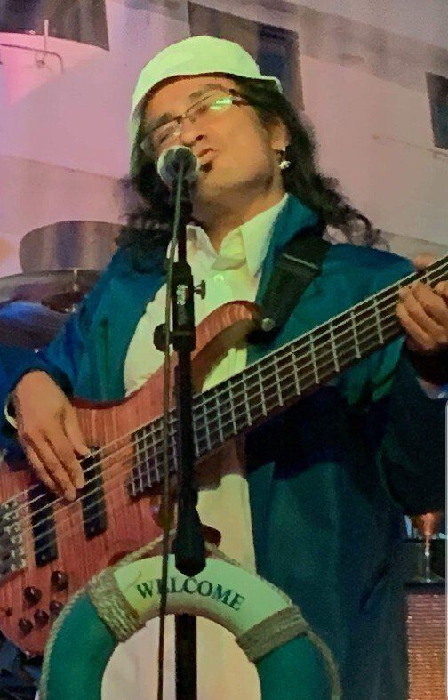 A man is singing into a microphone while playing a bass guitar