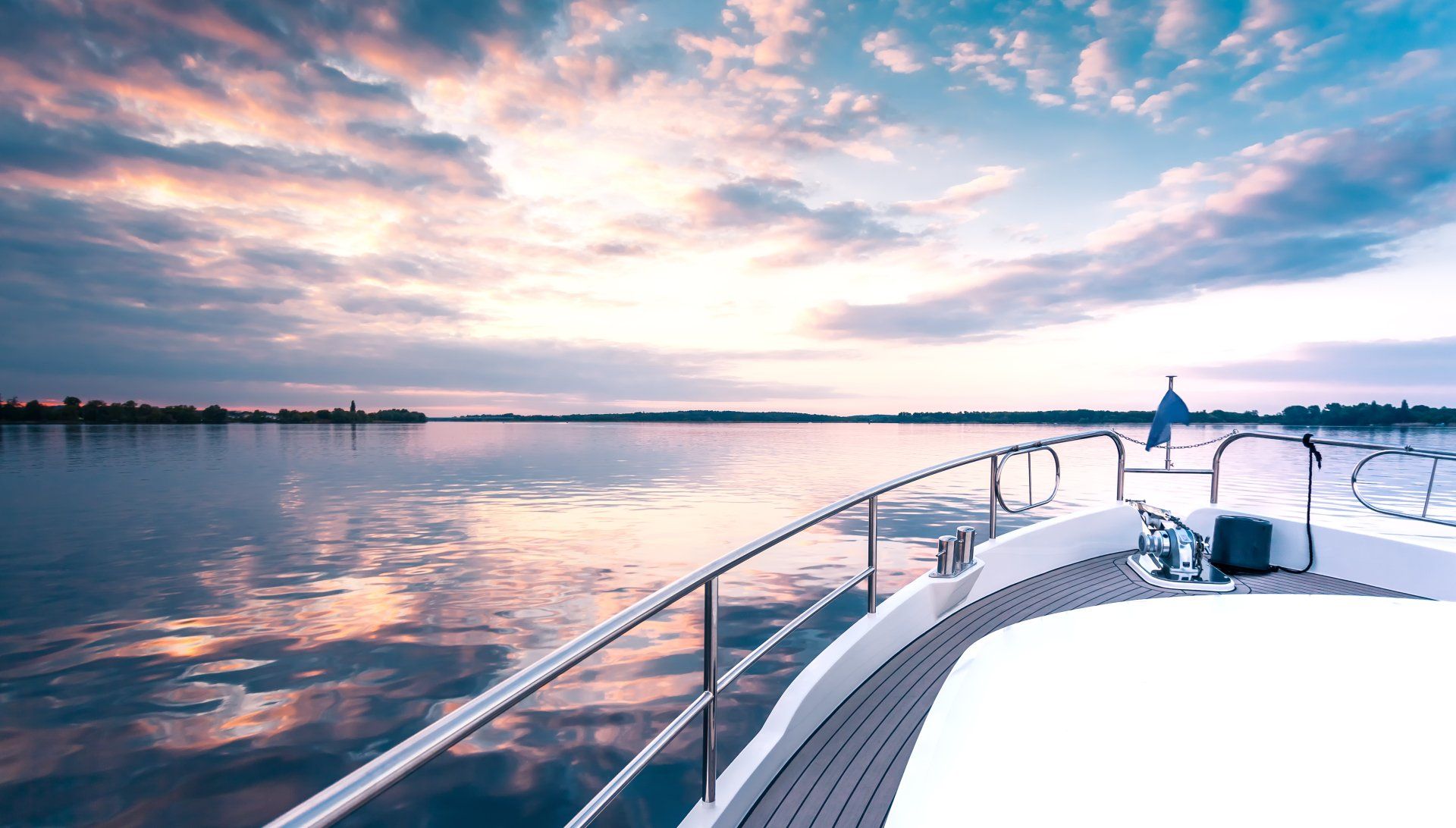 A boat is floating on top of a body of water at sunset.